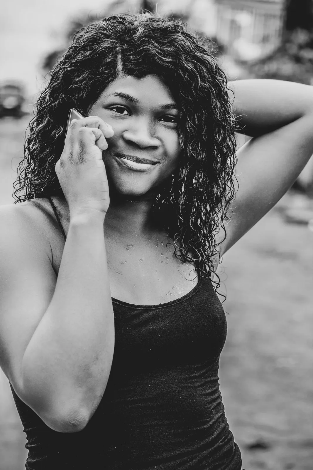 A woman smiling on a phone call, in black and white.