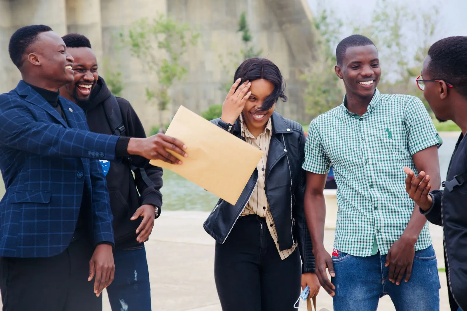 Five friends laughing together outdoors.