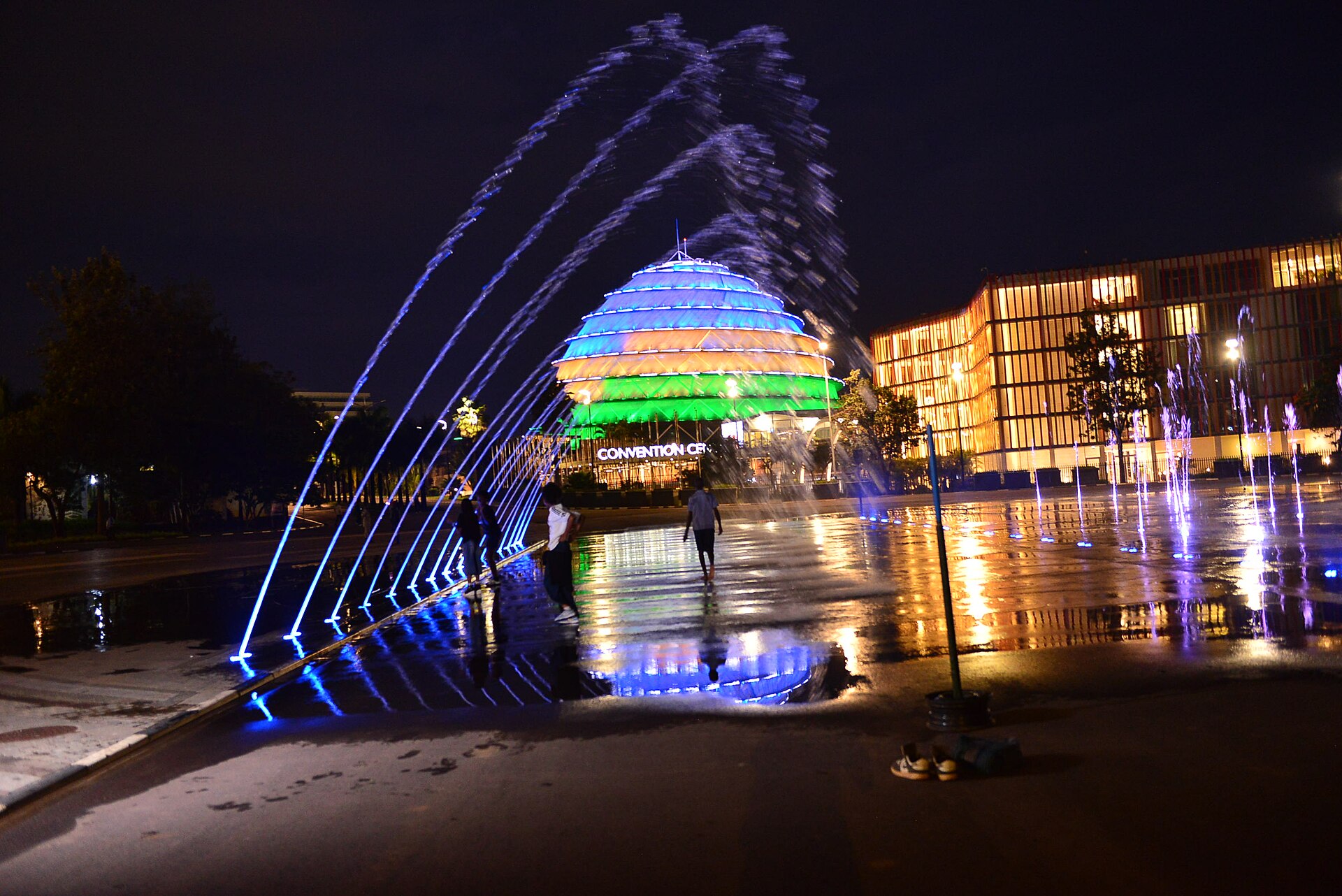 The Kigali Convention Centre lit up at night behind dancing fountains.