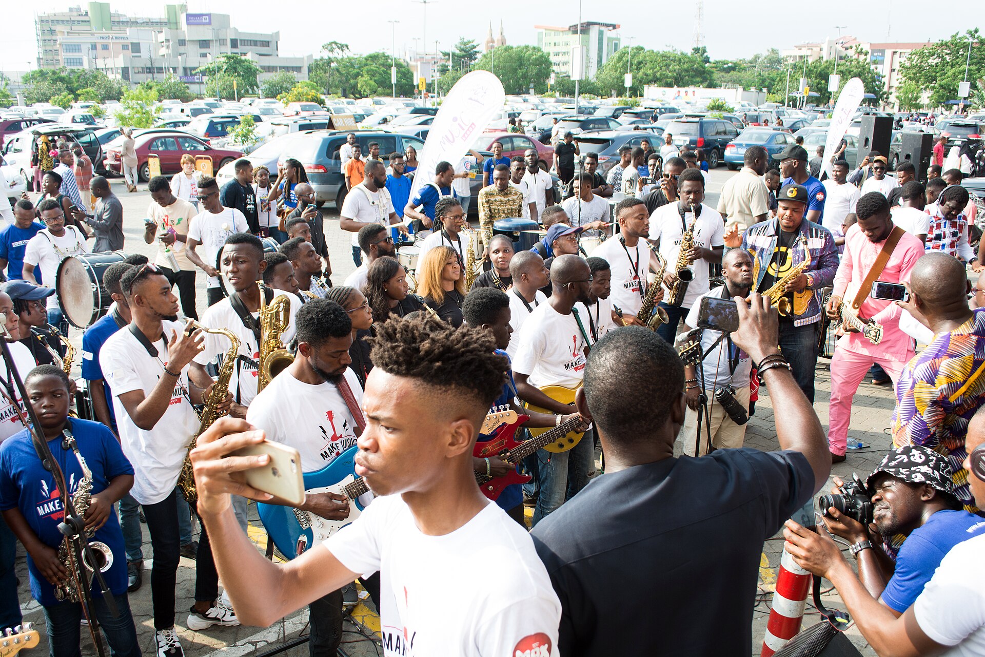 Young people in Lagos filming a live street band on their phones.