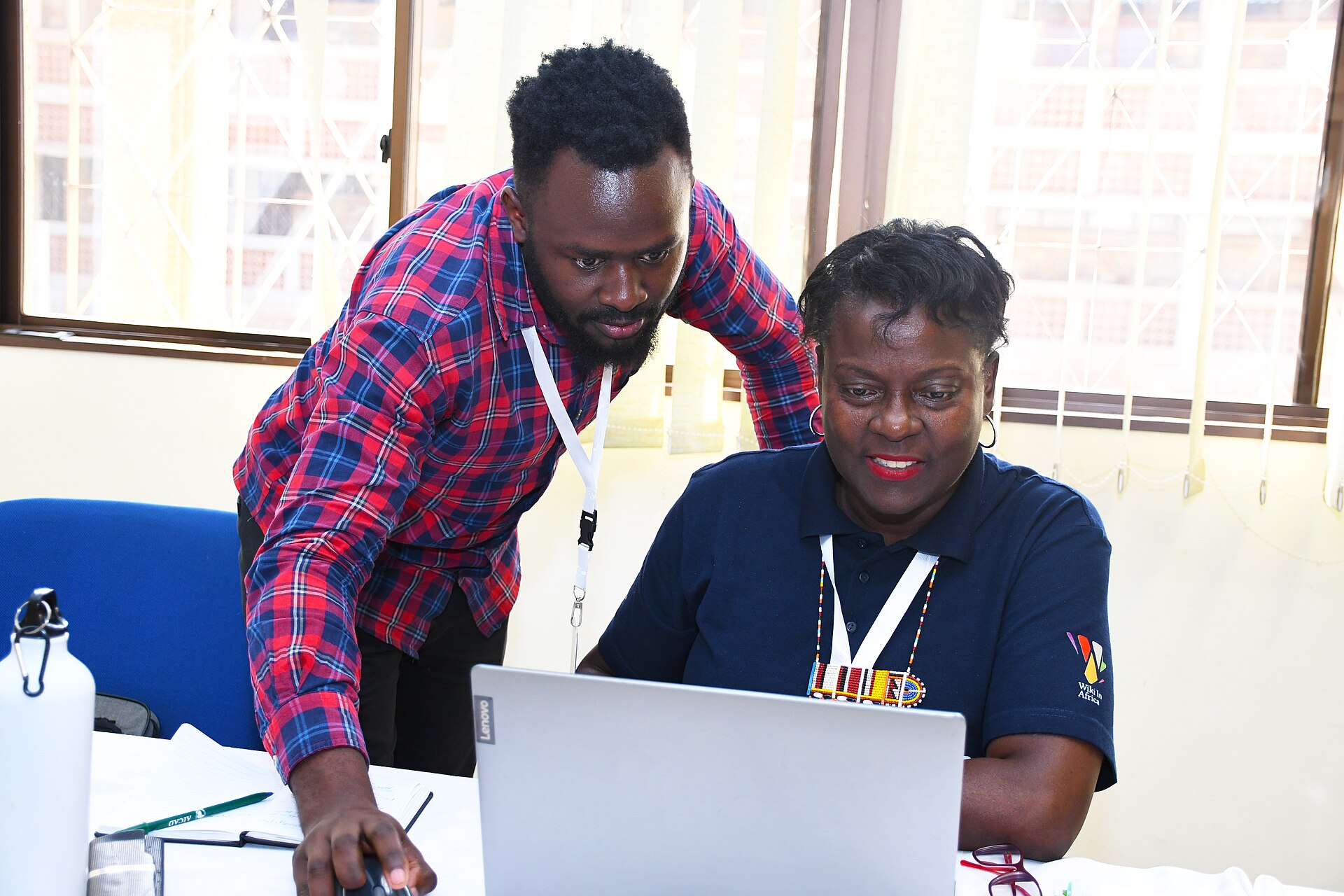 Two colleagues in Nairobi smiling over a laptop.